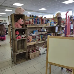 Winkelvloer met houten stellingen vol speelgoed, poppen en kinderartikelen onder fluorescente verlichting