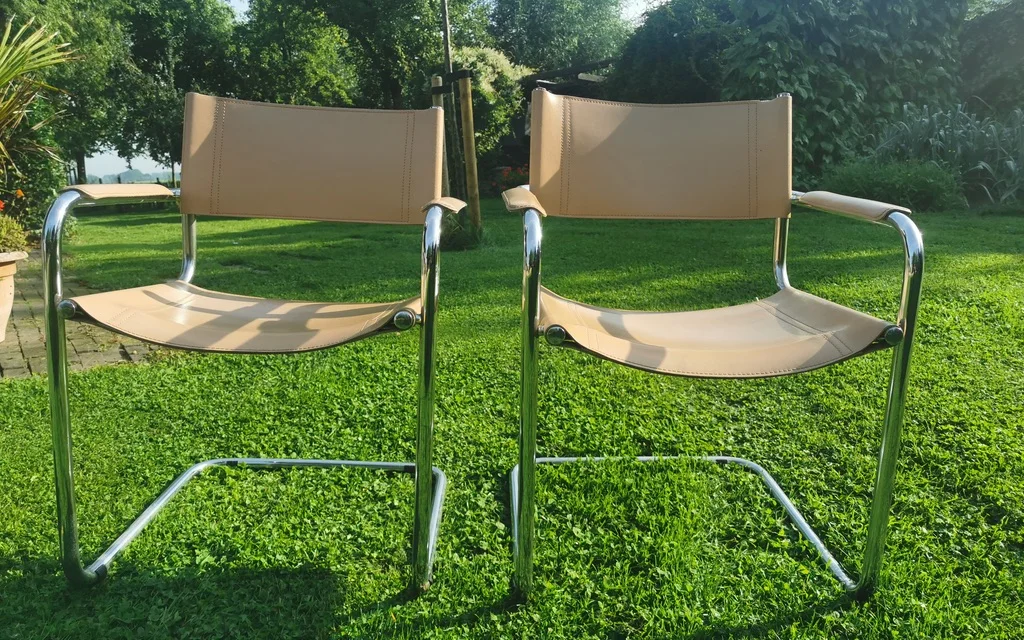 Twee vintage buisframe stoelen met beige zitting en rug op een grasveld