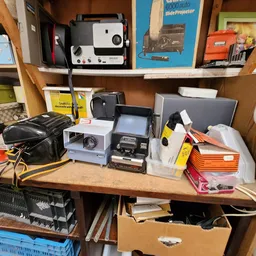 Tafel vol met elektronische apparaten en accessoires: speakers, devices en kabels